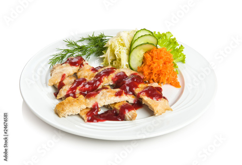 Sliced pork chop with cowberry sauce and vegetable side dish.