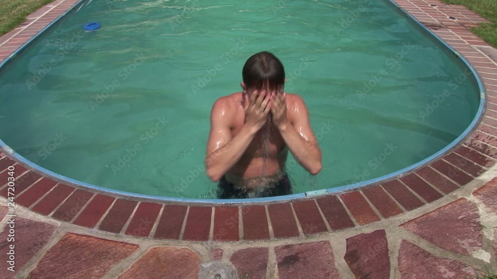 Junger Mann steigt aus dem Swimmingpool