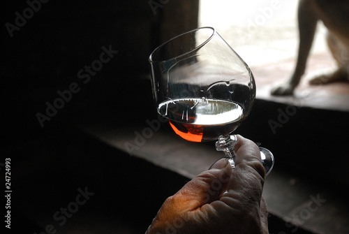 right hand holding a glass of brandy with a dark background photo