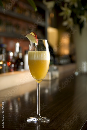 Bellini Champagne Cocktail with apple slice in bar setting.