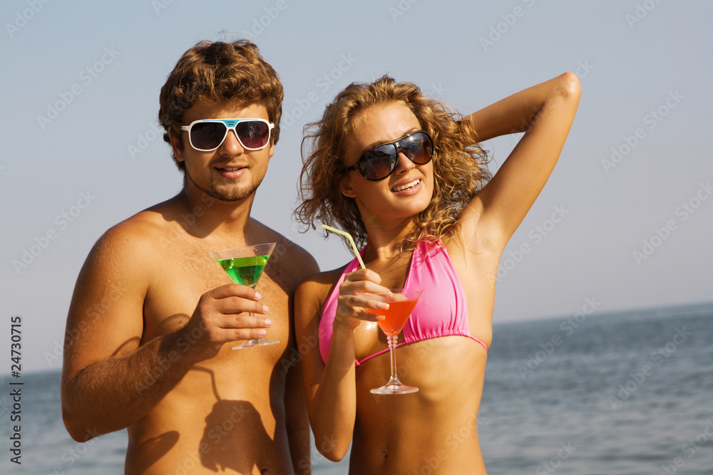 Young couple on the seaside with cocktails Young couple on the seaside with cocktails