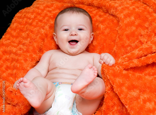 bambino che gioca su una coperta arancione photo