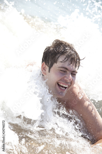 Young smiling men on waves at beach. © Masson