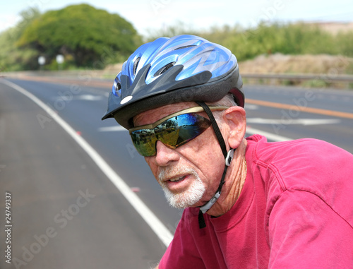 Athletic senior man riding a bicycle wearing a blue helmet © John Orsbun