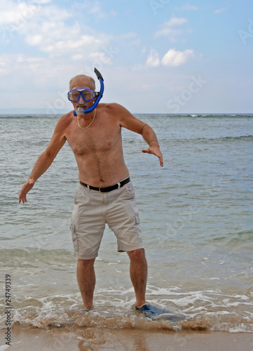 Retired senior man on beach with diving gear
