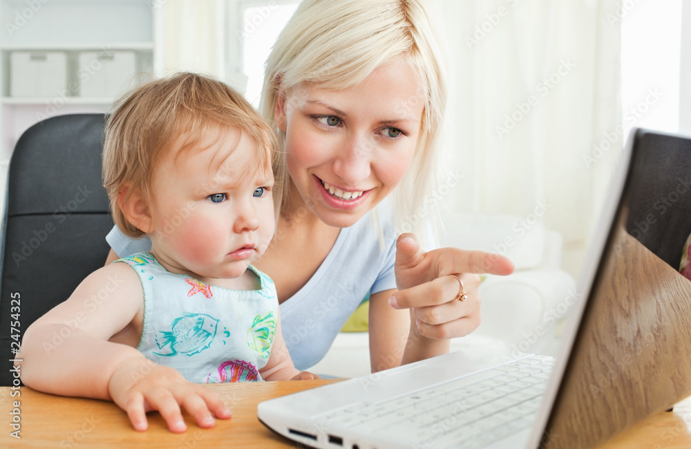 Blond mother having fun with her daughter in front of the laptop Blond mother having fun with her daughter in front of the laptop