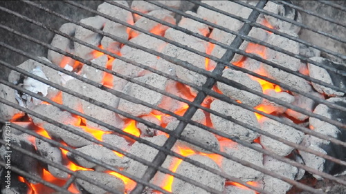 flaming charcoal briquettes on barbecue kettle grill photo