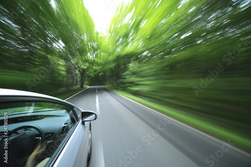 car driving fast into forest.