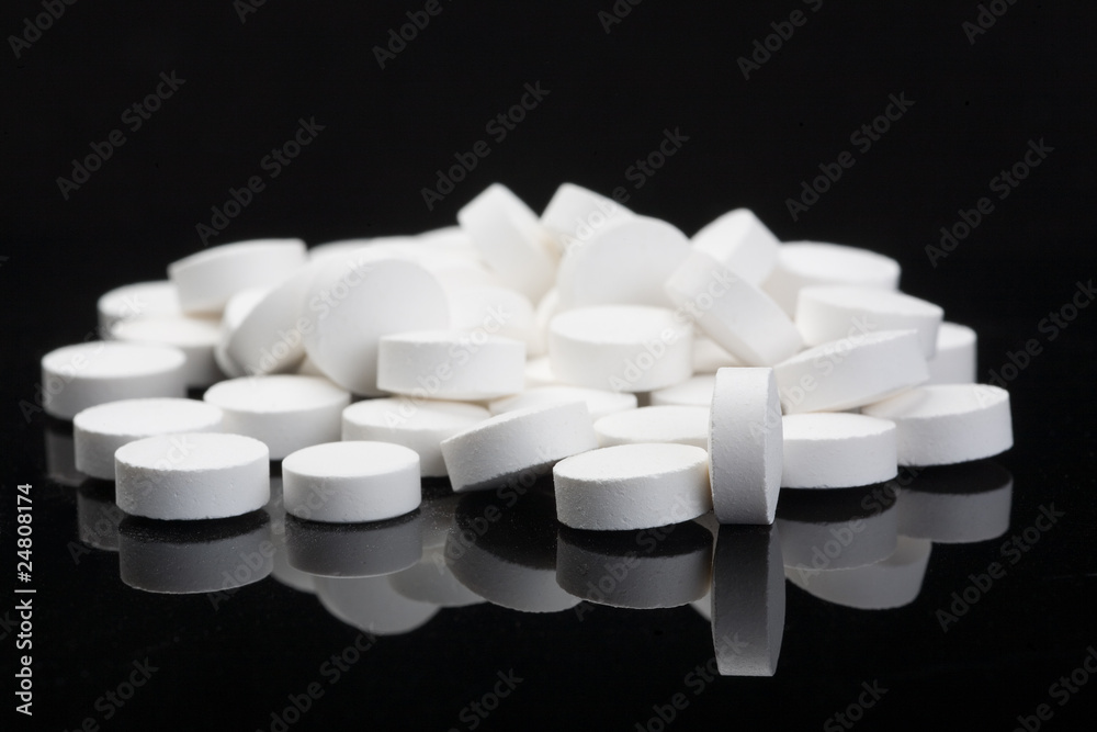 closeup with white pills, isolated on black background
