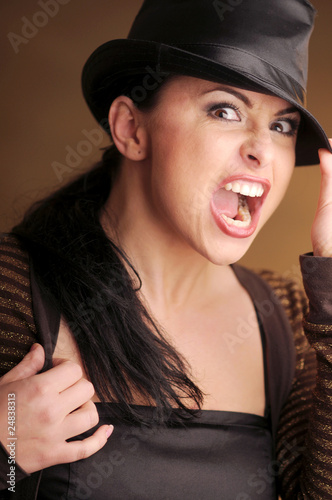 Atractive brunette woman in black hat on the brown bakground