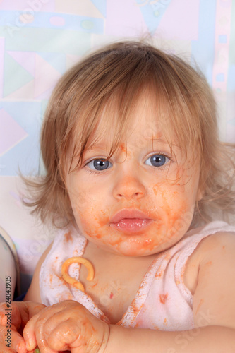 Messy baby girl eating spaghetti photo