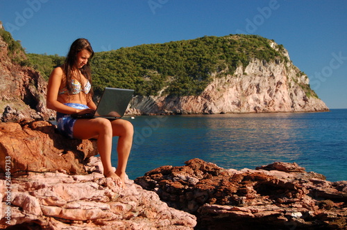 Dziewczyna z laptopem na skalistej plaży