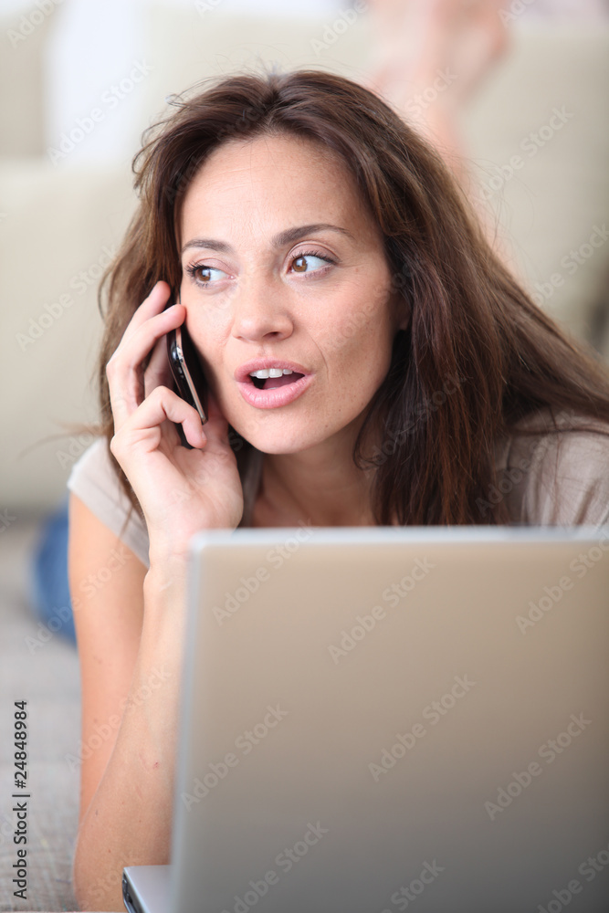 Woman on couch with laptop computer and telephone Woman on couch with laptop computer and telephone