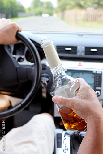 Drunk driver on a rural road with a bottle of alcohol in hand © wojtek
