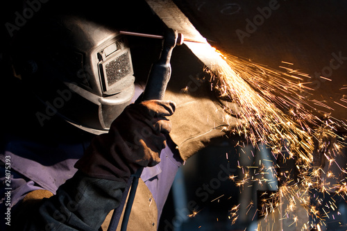 worker weld metal in factory and sparks