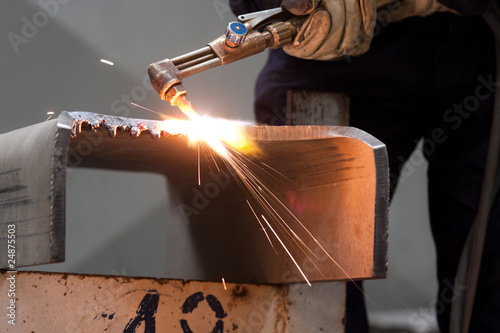 worker inside factory cut metal using blowtorch photo