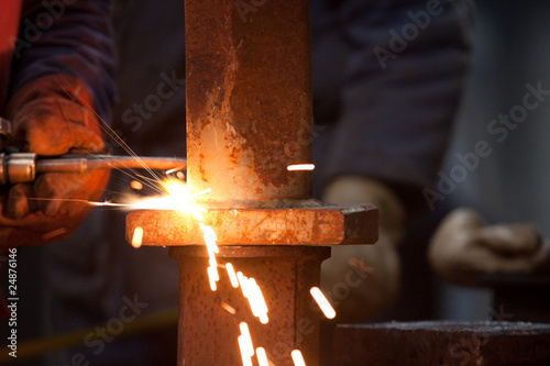 worker inside factory cut metal using blowtorch