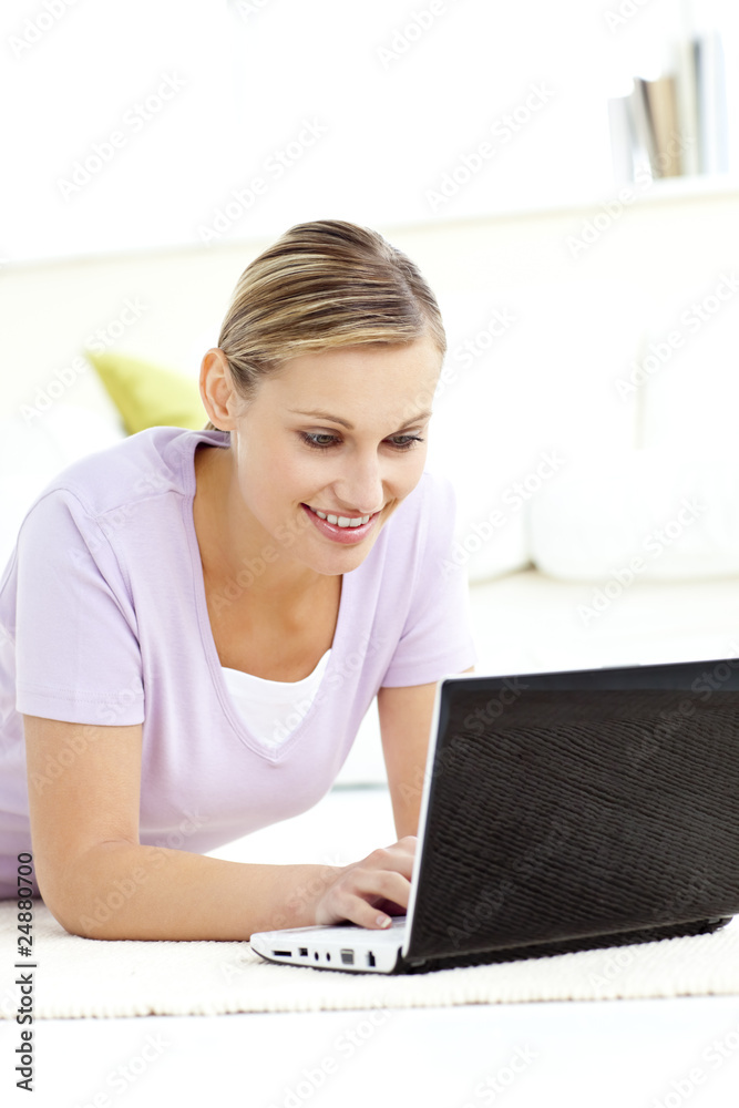 Radiant young woman using her laptop lying on the floor Radiant young woman using her laptop lying on the floor