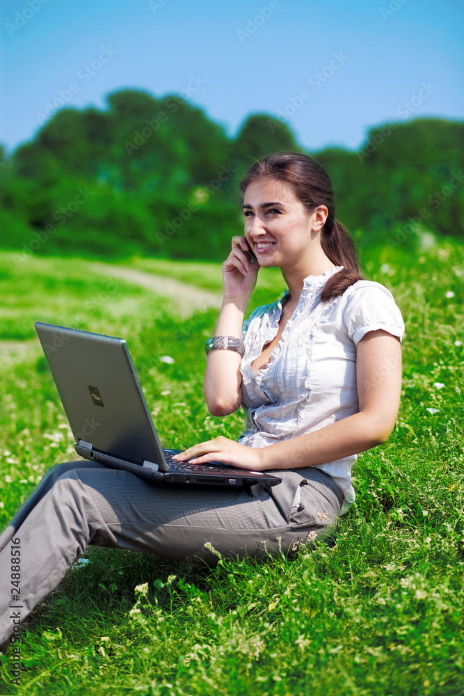 Beautiful  woman with phone and notebook on grass