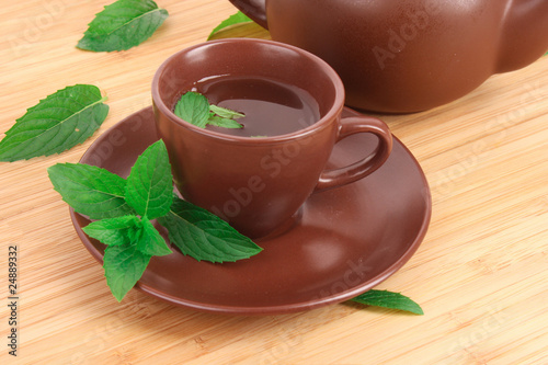 Cup of green tea on the saucer with mint on wooden surface photo