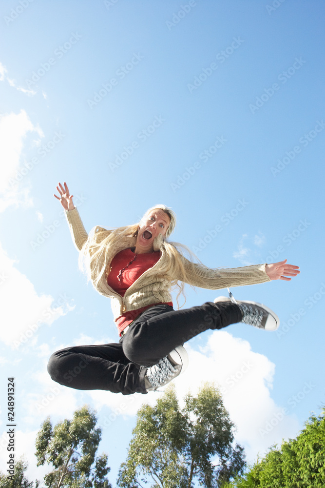 Young Woman Jumping On Trampoline Caught In Mid Air Young Woman Jumping On Trampoline Caught In Mid Air
