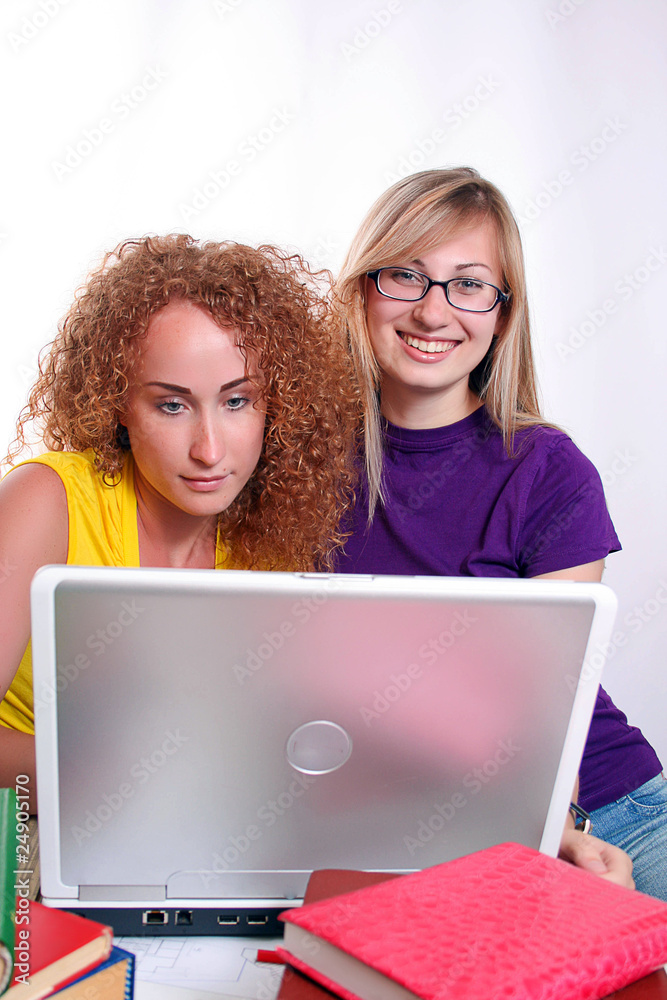 Two young student girls sitting at desk, learning