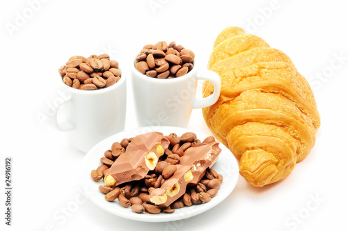 two cups and plate filled with coffee beans and croissant