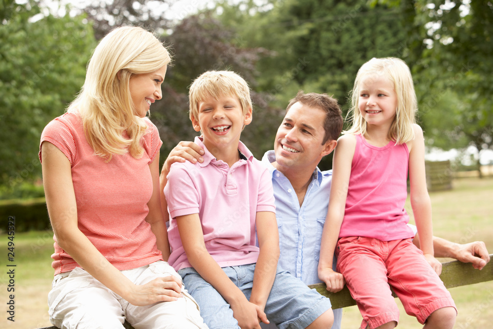 Portrait Of Family Sitting On Fence In Countryside Portrait Of Family Sitting On Fence In Countryside