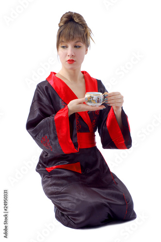 Pretty sitting girl in japan clothes with tea cup in hands