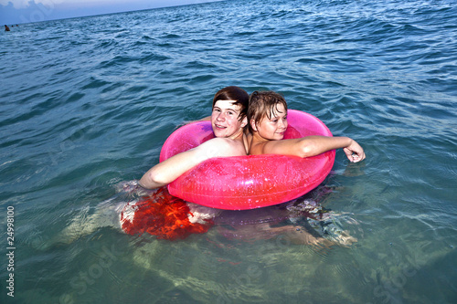 brothers in a swim ring have fun in the ocean