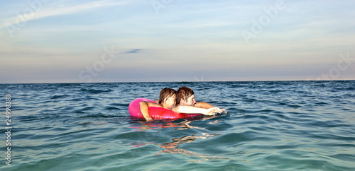 brothers in a swim ring have fun in the ocean