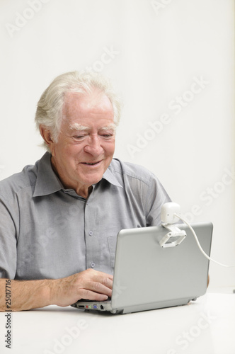 Älterer Herr mit Netbook und Webcam