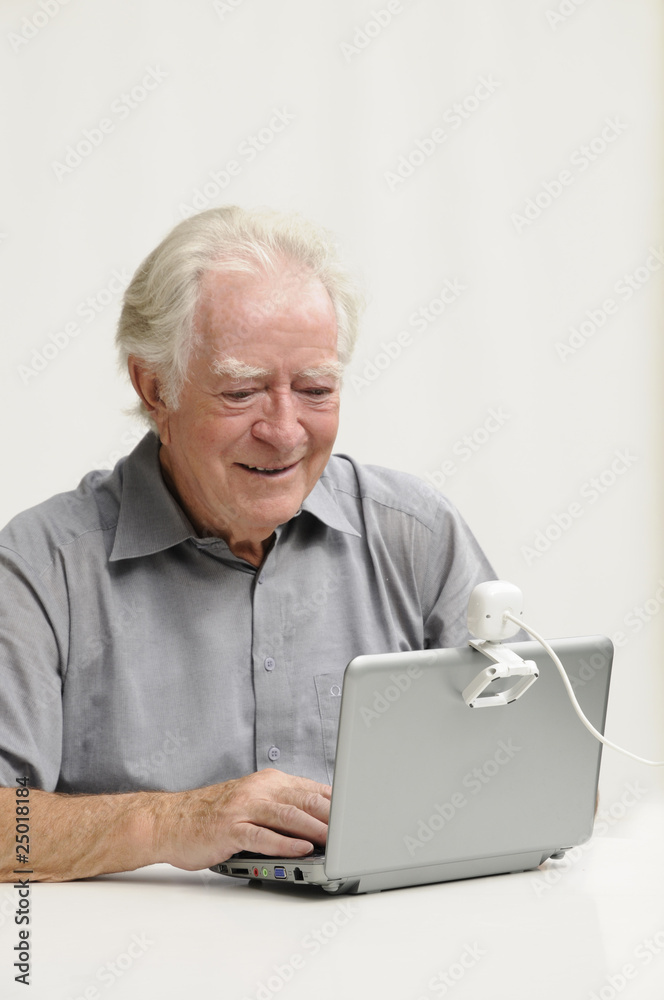 Älterer Herr mit Netbook und Webcam
