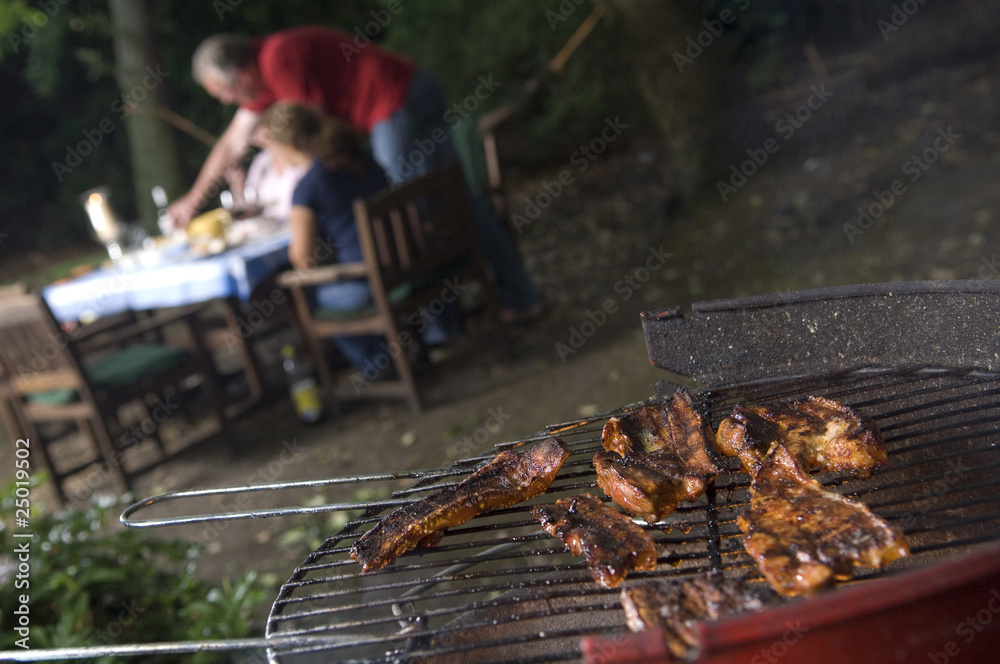 Fototapeta premium BBq with meat in foreground people in background