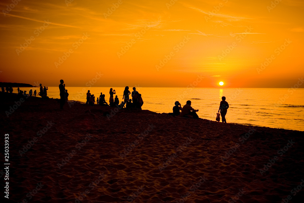Ludzie obserwujący zachód słońca nad morzem bałtyckim