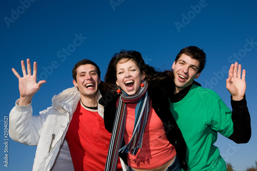 Happy laugh young team in warm clothes against a blue sky