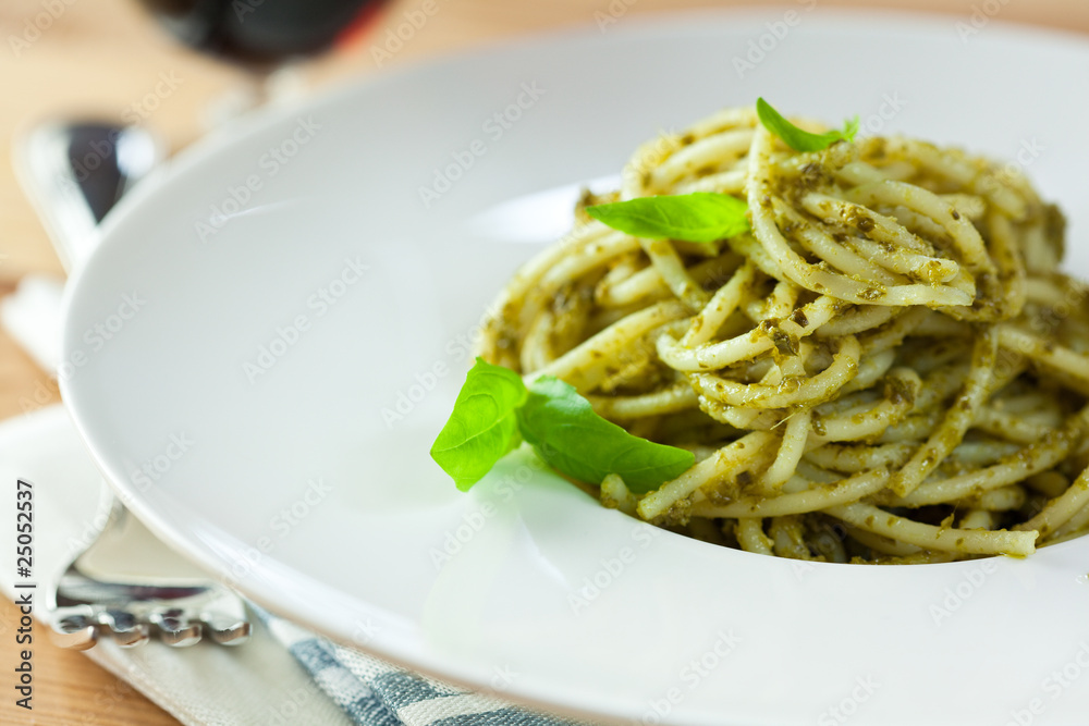 Close-up of spaghetti with pesto and fresh basil leaves