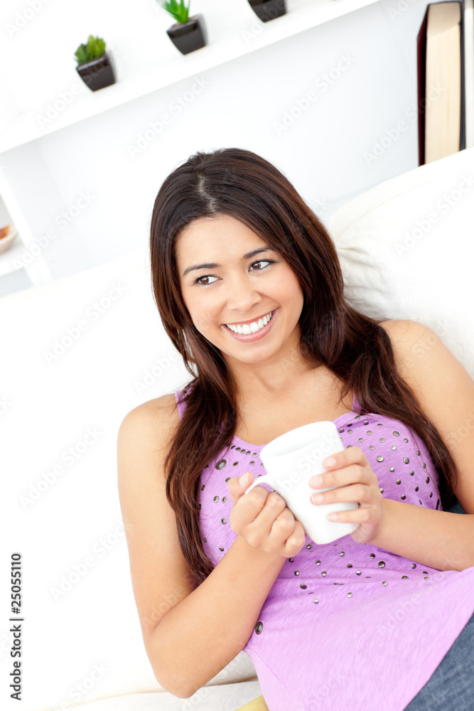 Relaxed woman holding a cup of coffee sitting on the sofa Relaxed woman holding a cup of coffee sitting on the sofa