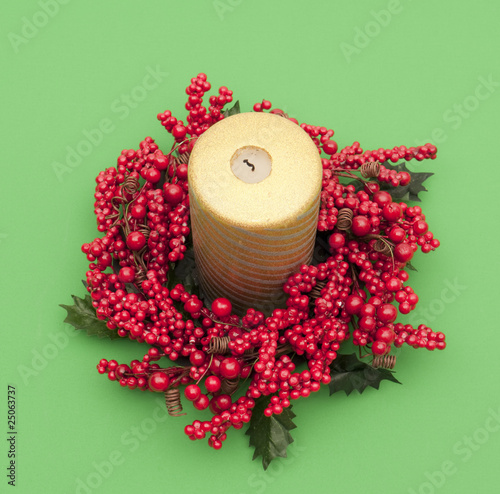 Christmas candle with artifial red berries on green photo