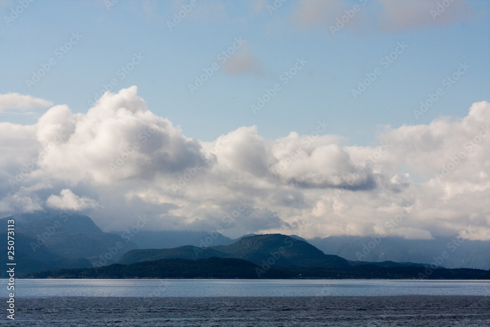 panorama with the sea, blue mountains and clouds with a blue sky in a summer day in Norway