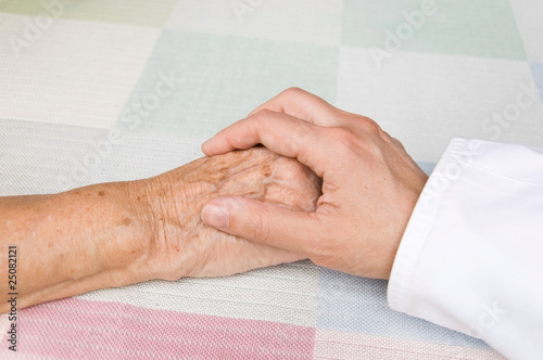 hand of a doctor holding the hand of an elderly patient