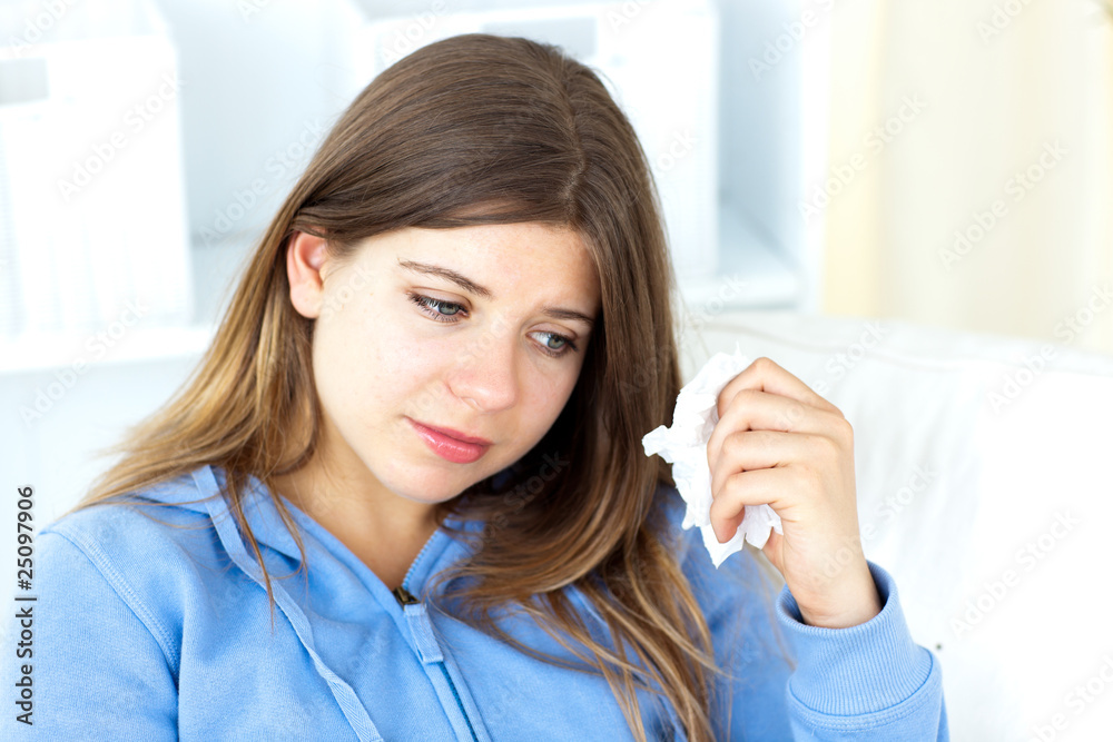 Sad young woman holding tissues sitting in the living-room Sad young woman holding tissues sitting in the living-room