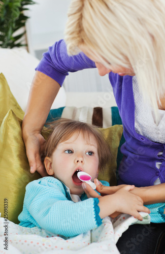 Sick little girl getting syrup from her caring mother photo