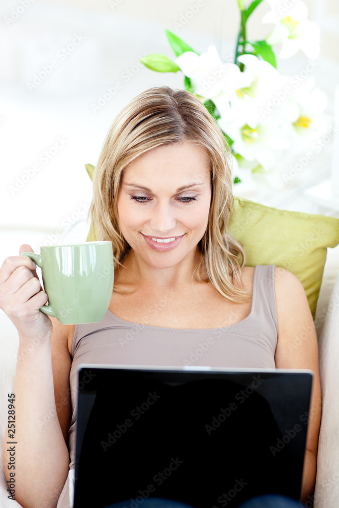 Caucasian woman sitting in front of her laptop and holding a cup Caucasian woman sitting in front of her laptop and holding a cup