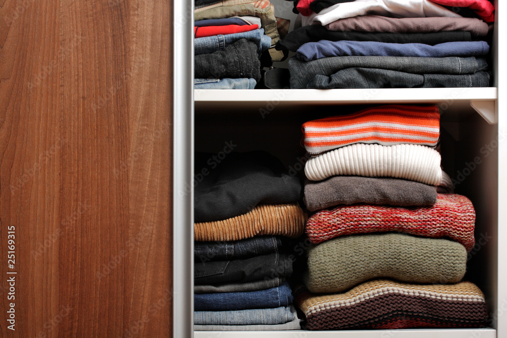 Open wardrobe with lots of folded clothes Open wardrobe with lots of folded clothes