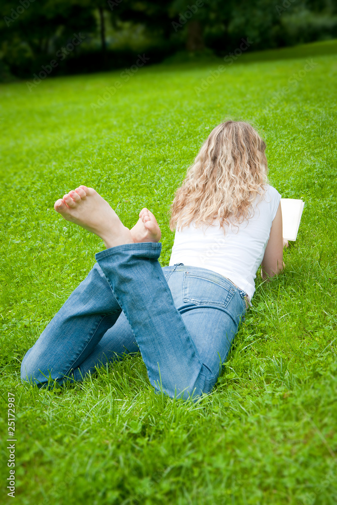 Fototapeta premium Junge Frau mit blonden Locken liest ein Buch