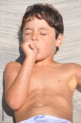 petit garçon suçant son pouce qui fait la sieste au soleil
