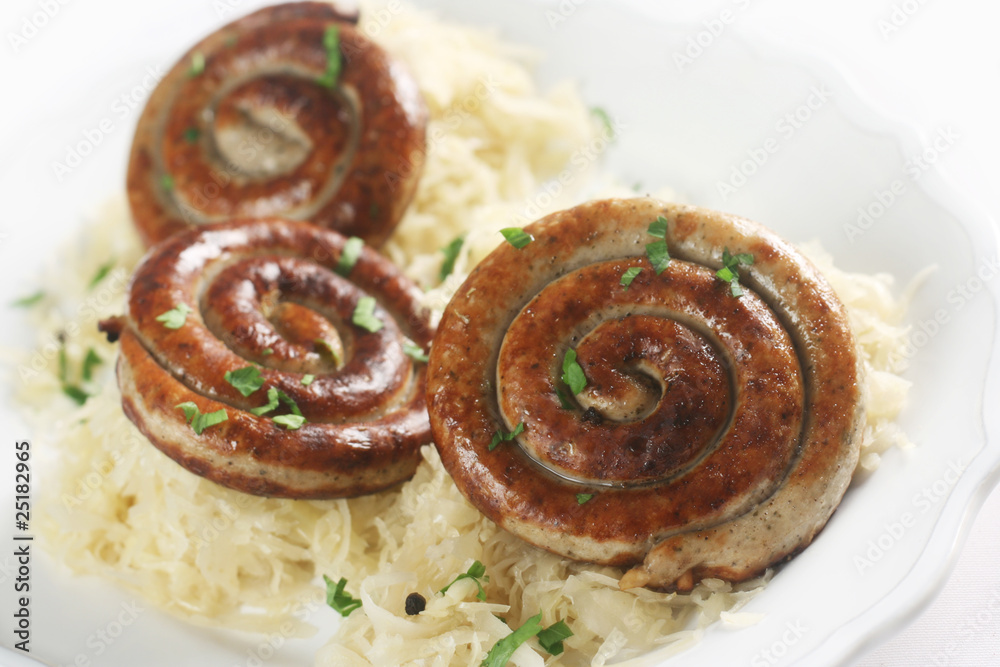 Fototapeta premium German Cuisine - Spiral-Shaped Bratwursts with Sauerkraut