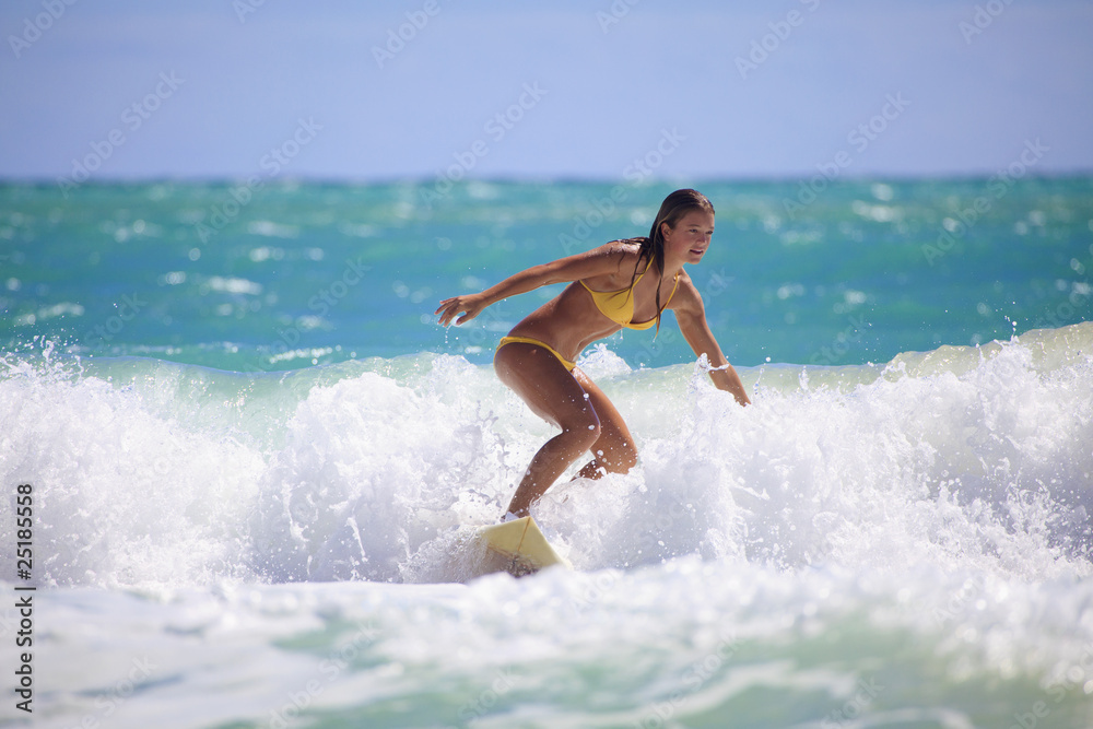 teenage girl in a yellow bikini surfing in Hawaii - obrazy, fototapety, plakaty 