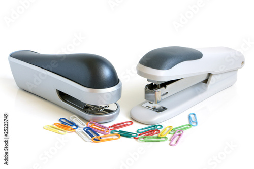 Two staplers and multicolored paper clips